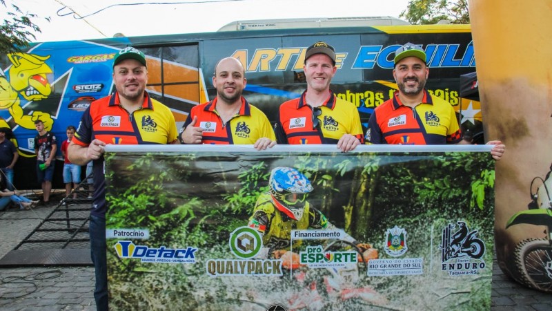pilotos seguram banner com logos dos patrocinadores