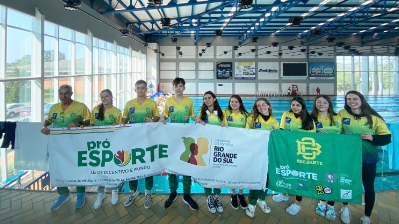 Equipe Natação Brilhante posa com o banner do Pró-Esporte