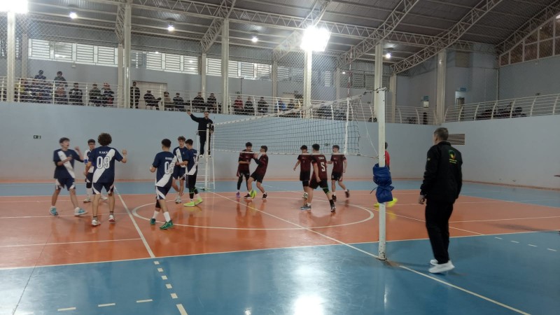 Jovens disputam partida de vôlei em ginásio