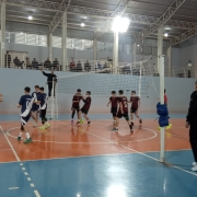 Jovens disputam partida de vôlei em ginásio