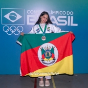 Jovem posa com medalha e bandeira do Rio Grande do Sul