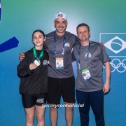 Jovem posa para foto com medalha ao lado de dois homens